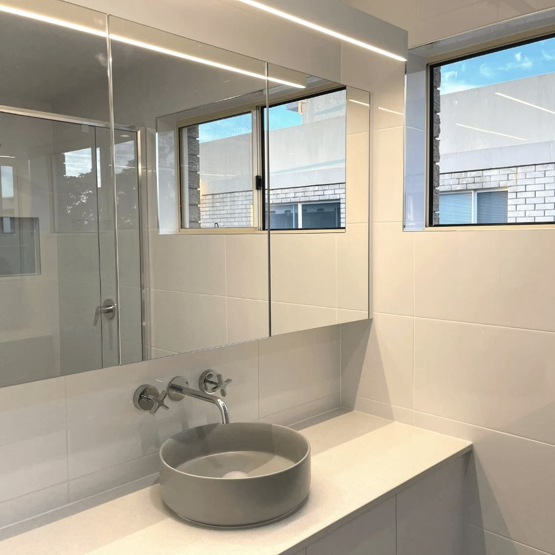 A Bright And Clean Bathroom With A Large Mirror — Nyblad Construction in Caloundra West, QLD