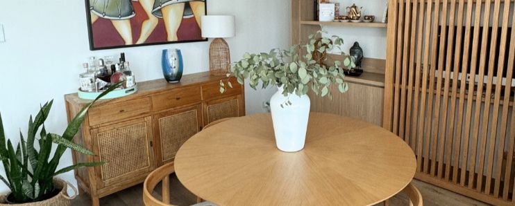 A Round Wooden Table With A Vase Of Flowers On It In A Living Room — Nyblad Construction in Caloundra West, QLD
