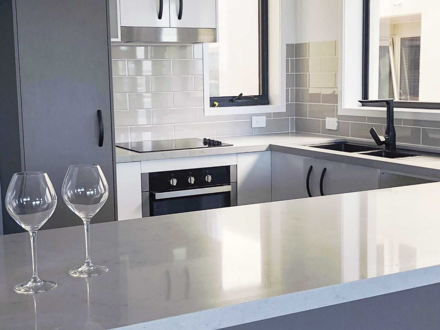 Two Wine Glasses Are Sitting On A Counter In A Kitchen — Nyblad Construction in Caloundra West, QLD
