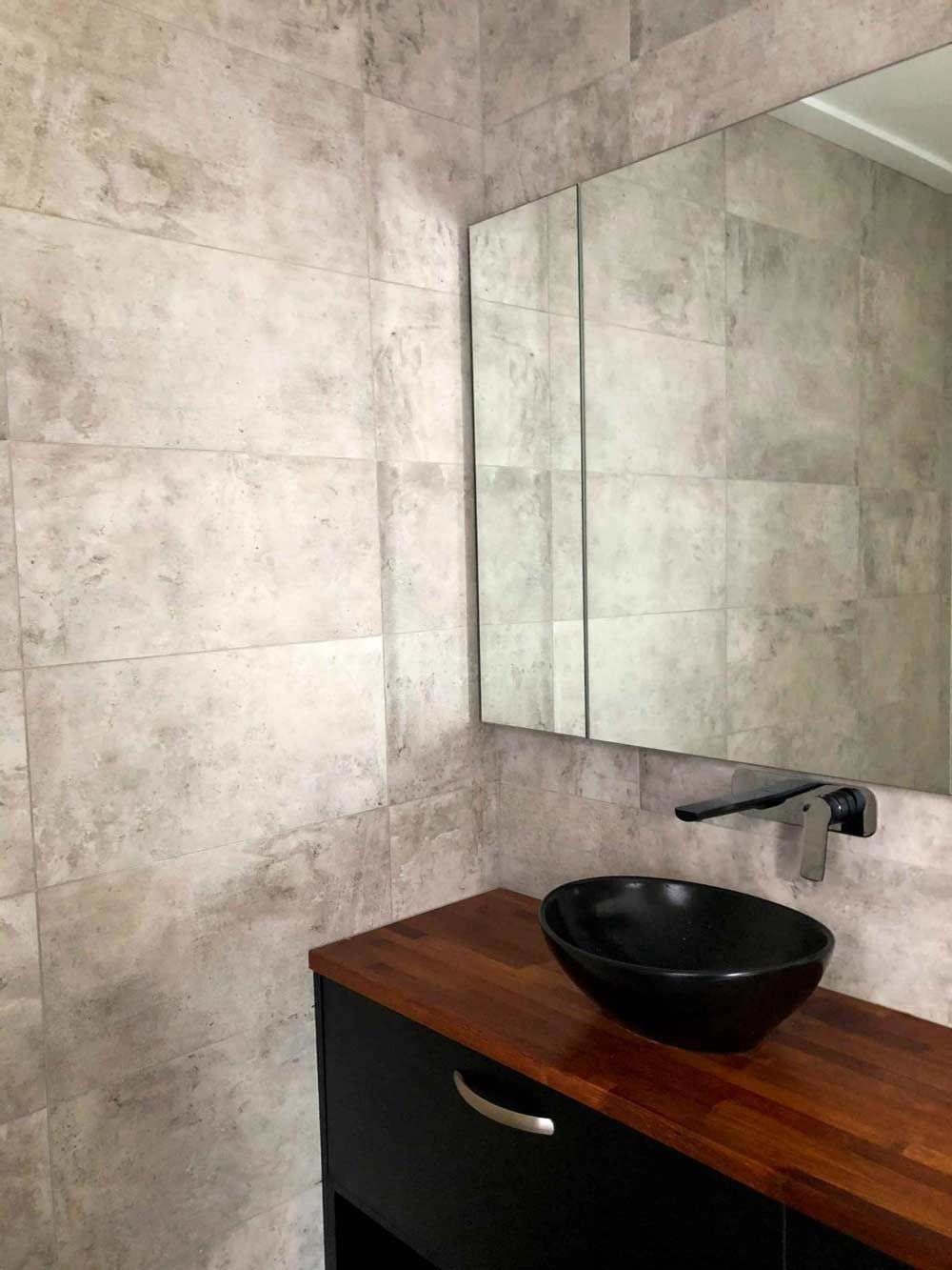 A Sleek Black Sink Sits Atop A Wooden Counter In The Bathroom Near A Mirror — Nyblad Construction in Caloundra West, QLD