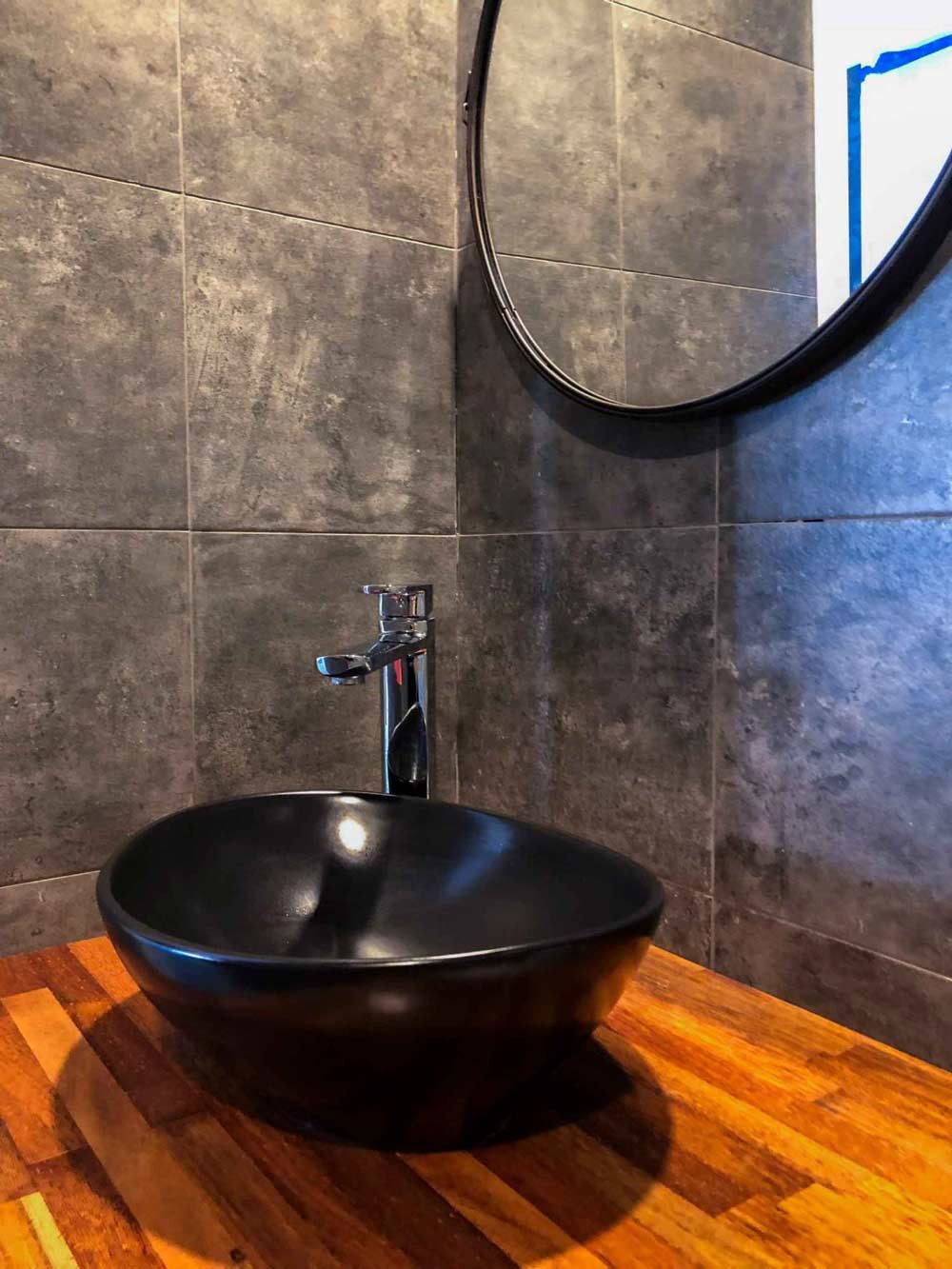 A Black Sink Rests On A Wooden Counter In The Bathroom Beside A Mirror — Nyblad Construction in Caloundra West, QLD