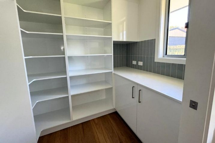  Kitchen With White Empty Cabinets And Shelves And A Window — Nyblad Construction in Caloundra West, QLD