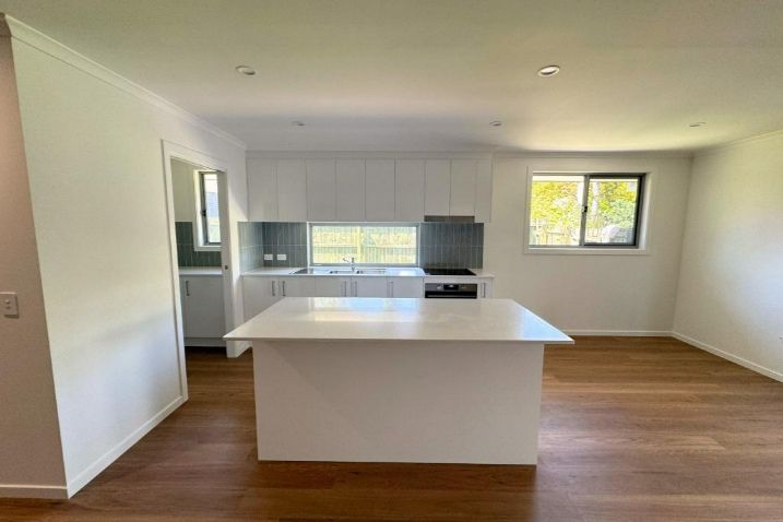 An Empty Kitchen With A Large Island In The Middle Of The Room — Nyblad Construction in Caloundra West, QLD