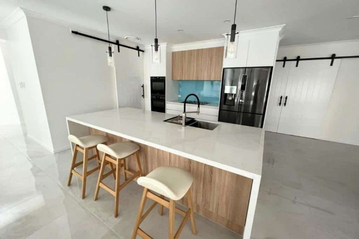 A Kitchen With A Large Island  And Three Stools — Nyblad Construction in Caloundra West, QLD