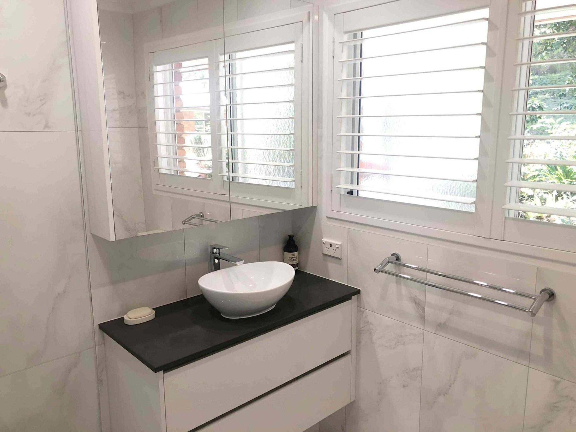A Bathroom With A Sink And Cabinet Beside The Window With Plantation Shutters — Nyblad Construction in Caloundra West, QLD