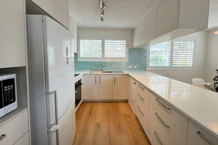 A Kitchen With White Cabinets, A Refrigerator And A Microwave — Nyblad Construction in Caloundra West, QLD