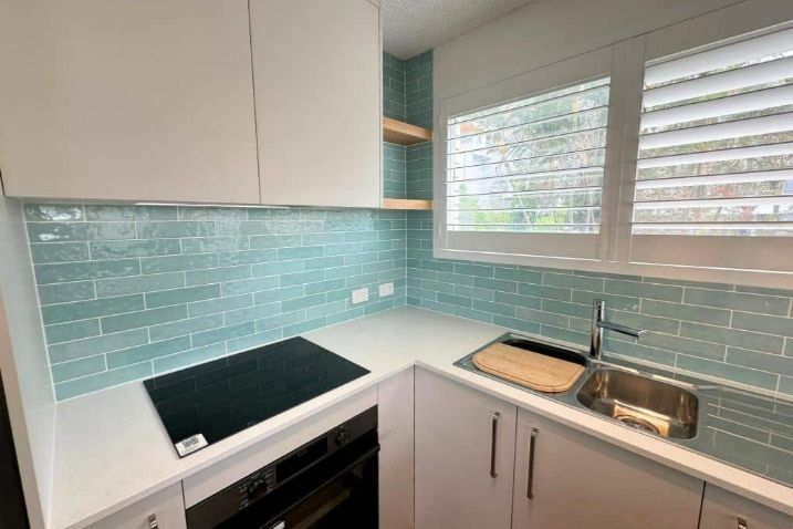 A Kitchen With White Cabinets And Blue Wall Tiles — Nyblad Construction in Caloundra West, QLD