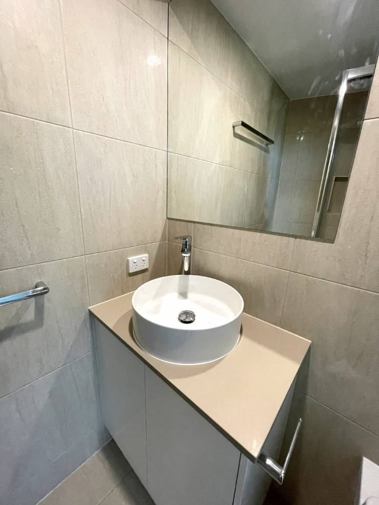 A Bathroom With A Small Round Sink And A Mirror — Nyblad Construction in Caloundra West, QLD