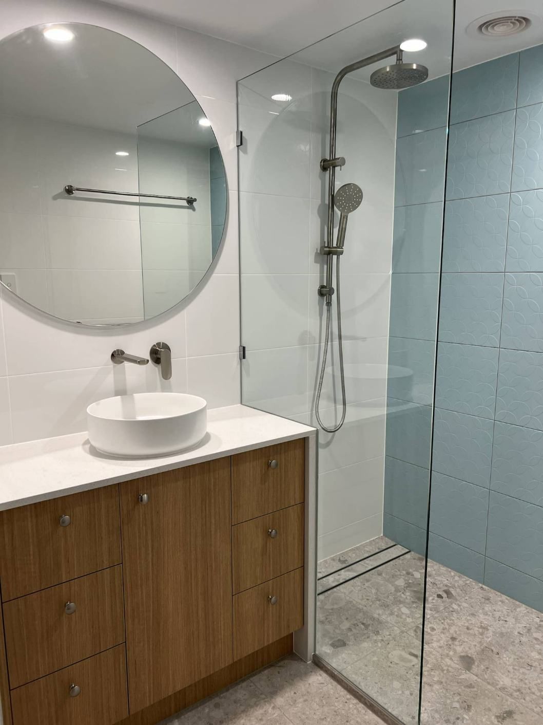 A Bathroom Detail With A Brown Cabinet And Black Circular Mirror — Nyblad Construction in Caloundra West, QLD