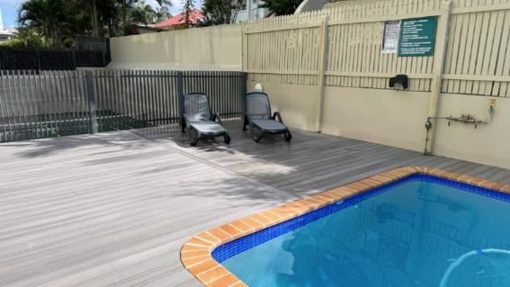A Small Swimming Pool Surrounded By Chairs And A Wooden Deck — Nyblad Construction in Caloundra West, QLD