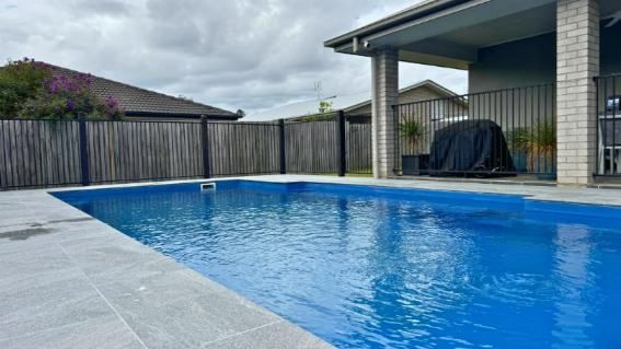 There Is A Large Swimming Pool In The Backyard Of A House — Nyblad Construction in Caloundra West, QLD