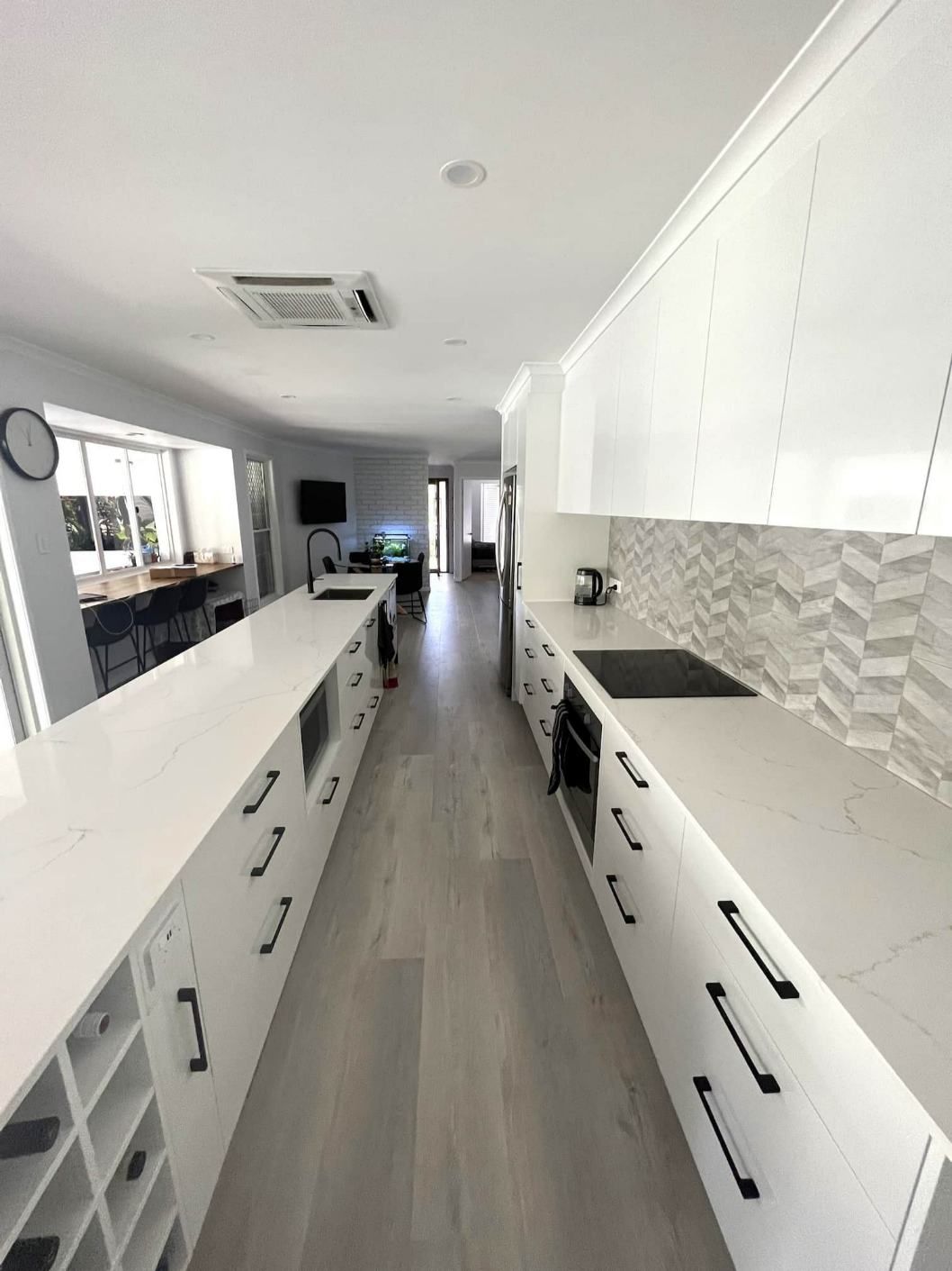 A Long Kitchen With White Cabinets And Black Handles — Nyblad Construction in Caloundra West, QLD
