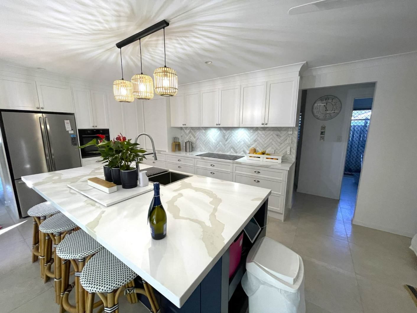 A Kitchen With A Large Island, Stool, And Bottle Of Wine On The Counter — Nyblad Construction in Caloundra West, QLD