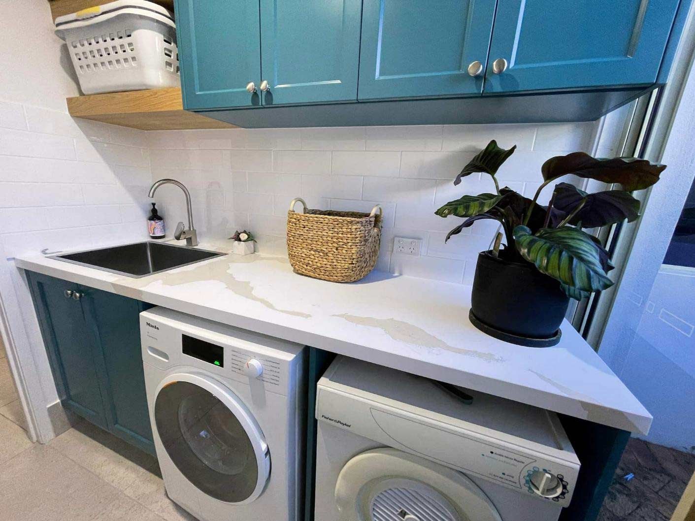 A Laundry Room With A Washing Machine, Dryer, Sink And Potted Plant — Nyblad Construction in Caloundra West, QLD