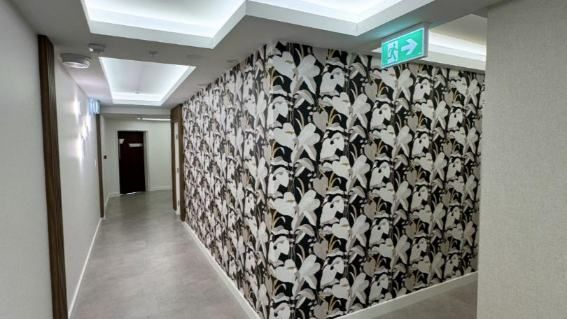 A Hallway With A Patterned Wall And A Green Exit Sign — Nyblad Construction in Caloundra West, QLD