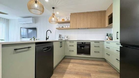 A Kitchen A Black Refrigerator, A Black Dishwasher, And A Wooden Floor.
