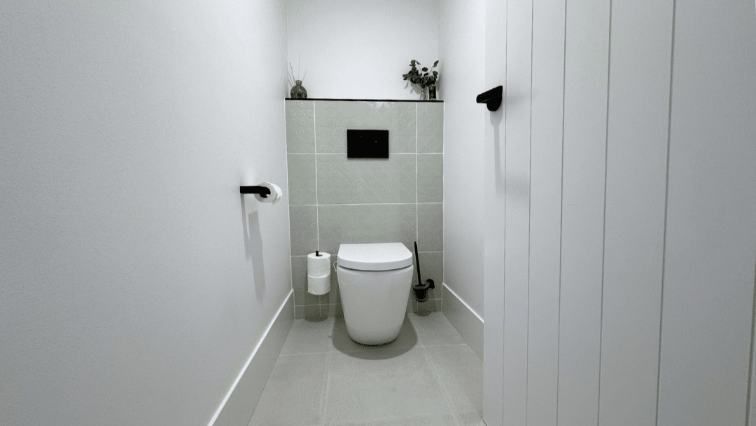 A Small Bathroom With A Toilet And A Paper Towel Holder — Nyblad Construction in Caloundra West, QLD