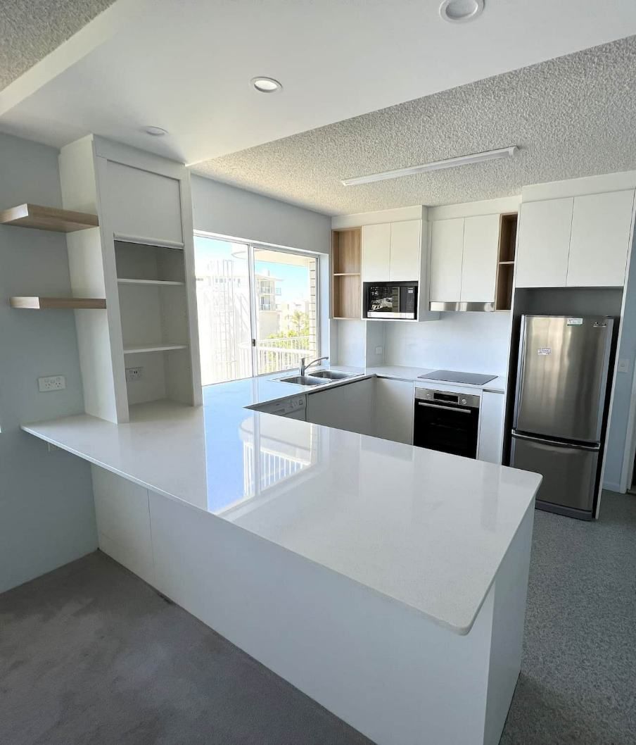  White Kitchen Cabinets And A Stainless Steel Refrigerator And Gas Range — Nyblad Construction in Caloundra West, QLD