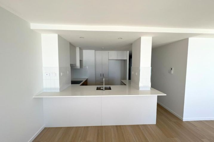 An Empty Kitchen With White Cabinets And A Sink — Nyblad Construction in Caloundra West, QLD