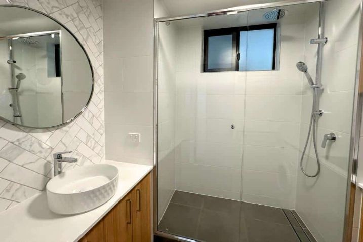 A Bathroom With A Sink, Mirror And Open Shower Area Room — Nyblad Construction in Caloundra West, QLD