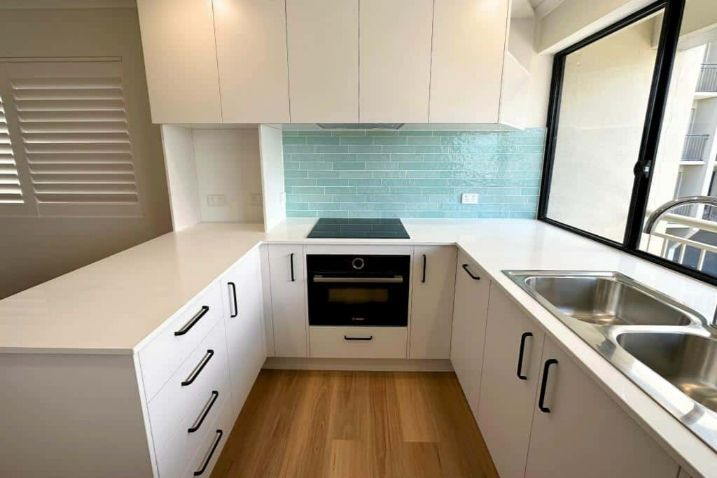 A Kitchen With White Cabinets And A Stove Top Oven — Nyblad Construction in Caloundra West, QLD