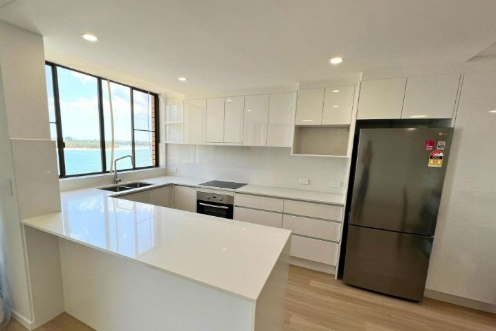 A Kitchen With White Cabinets And Black Refrigerator — Nyblad Construction in Caloundra West, QLD