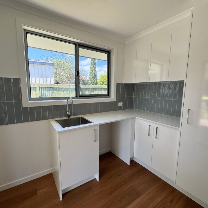 A Space With White Kitchen Cabinets, A Sink, And A Window — Nyblad Construction in Caloundra West, QLD
