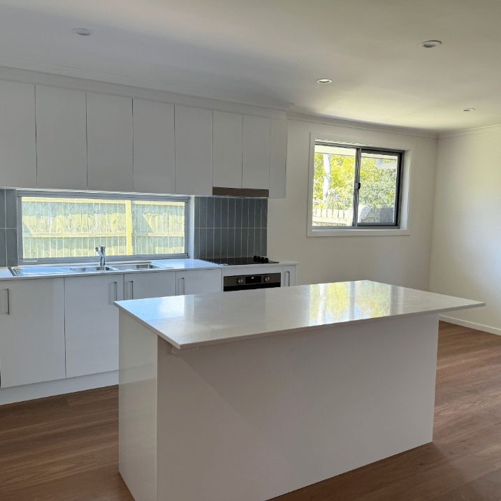  Kitchen With White Cabinets And A Large Island In The Middle — Nyblad Construction in Caloundra West, QLD