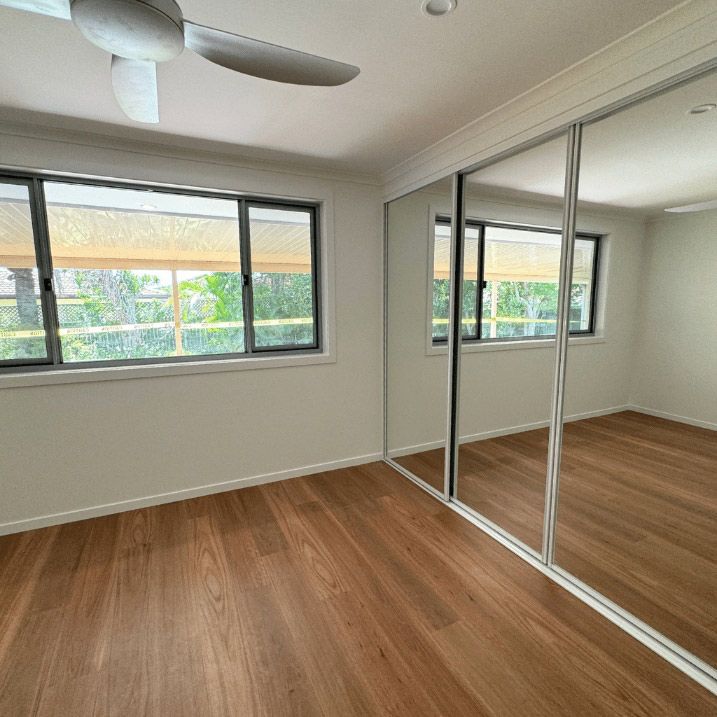 An Empty Room With A Ceiling Fan And Mirrors — Nyblad Construction in Caloundra West, QLD