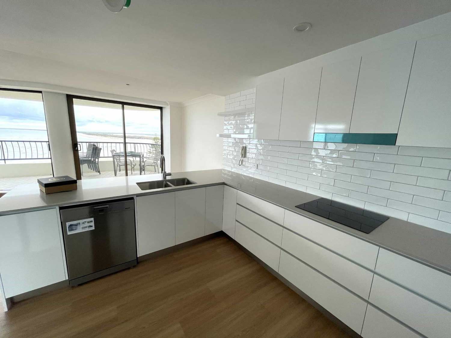 A Kitchen With Stove Top Oven, A Dishwasher And A Large Window — Nyblad Construction in Caloundra West, QLD