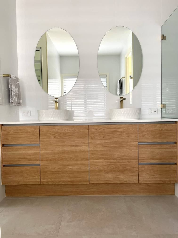 A Contemporary Bathroom With Two Sinks And Two Circular Mirrors — Nyblad Construction in Caloundra West, QLD