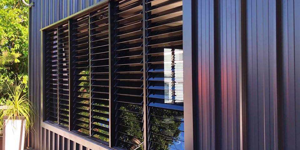 A Black Building With A Window And Shutters On It — Nyblad Construction in Caloundra West, QLD