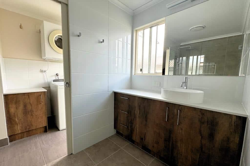Bathroom With a Sink, Mirror and Wooden Cabinets — Nyblad Construction in Caloundra West, QLD