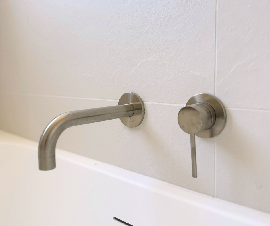 Brushed Nickel Faucet Set Over a White Bathtub Against White Tiled Wall — Nyblad Construction in Caloundra West, QLD