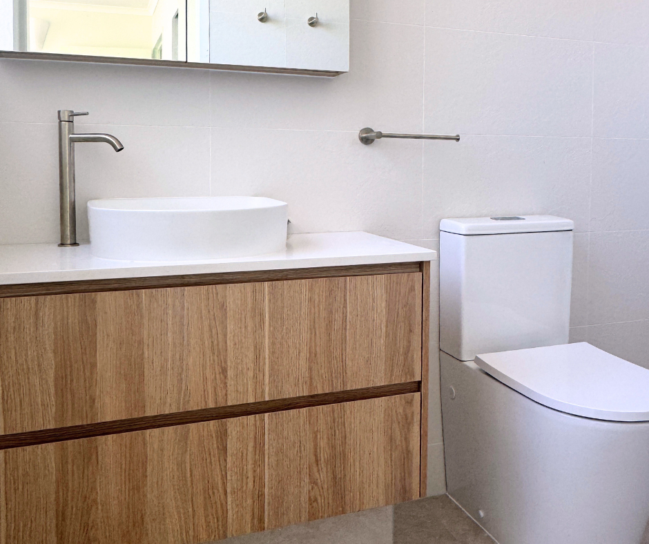 Modern Bathroom With a Wooden Vanity, White Countertop, Vessel Sink, and Toilet — Nyblad Construction in Caloundra West, QLD