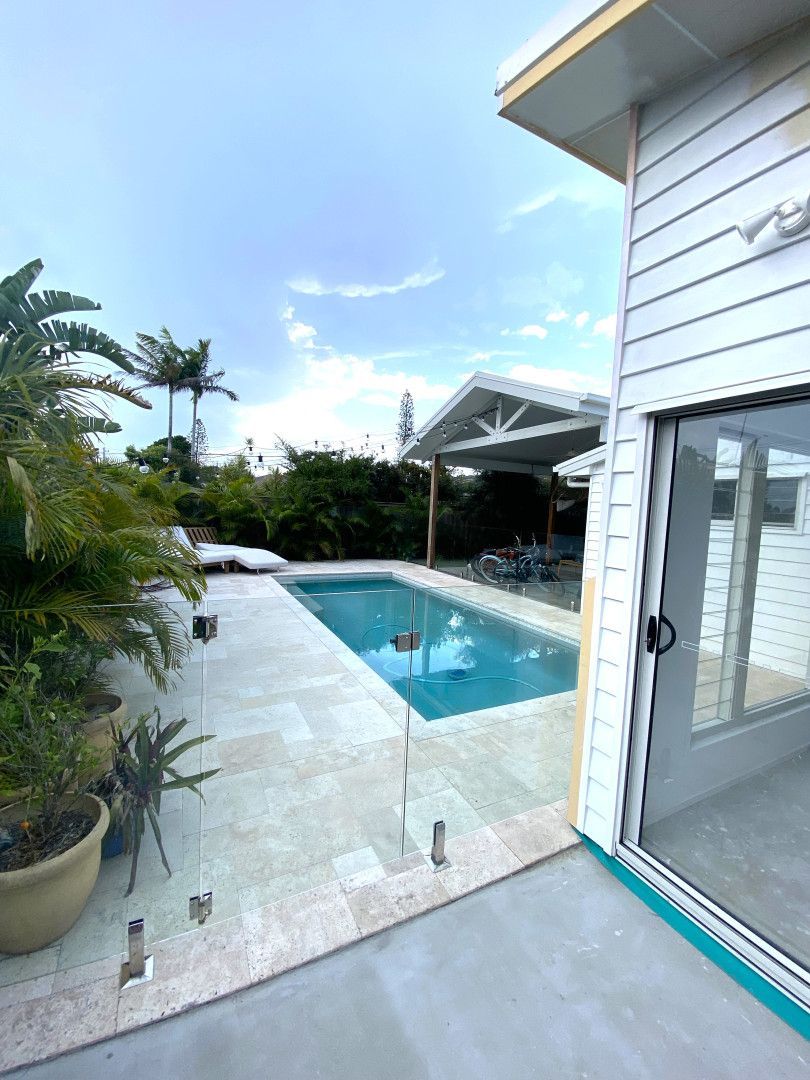 Pool area with blue water, white patio, glass fence, and covered seating. — Nyblad Construction in Maroochydore, QLD