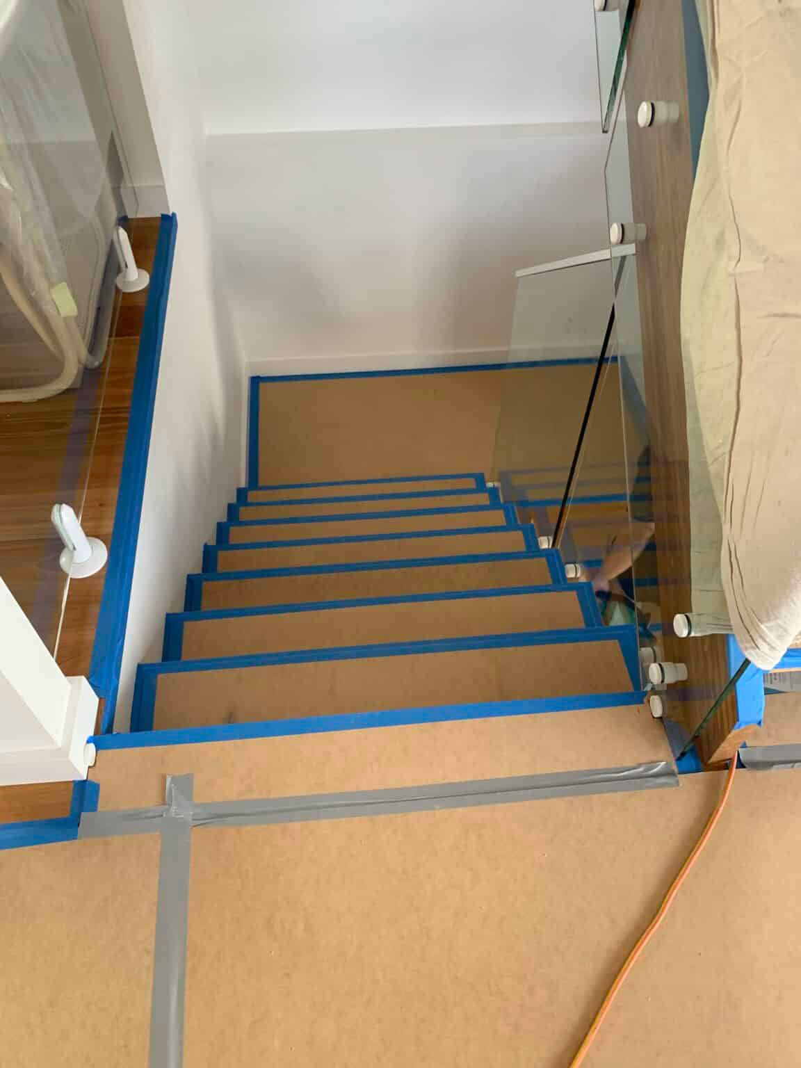 A Staircase Is Being Painted Blue And Has A Glass Railing — Nyblad Construction in Caloundra West, QLD