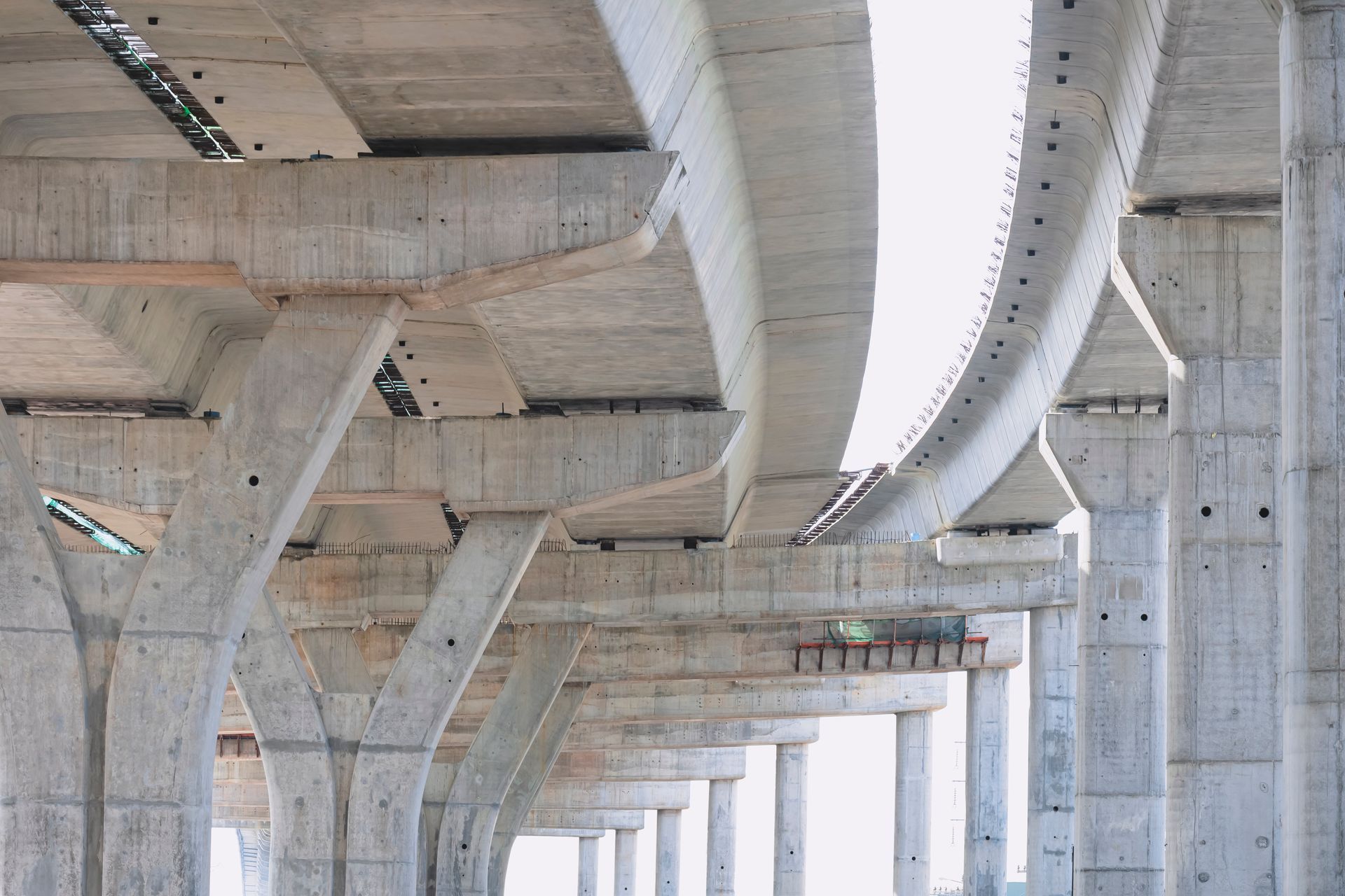 Concrete elevated highway under construction with curved overpass spans and support pillars