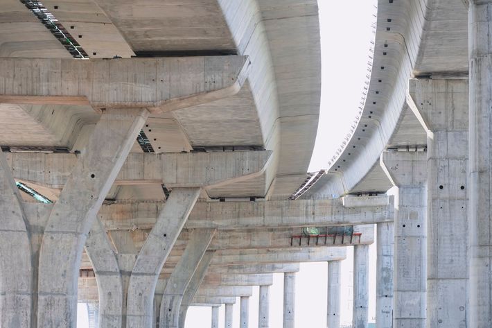 Concrete overpass under construction with massive support columns and curved roadways