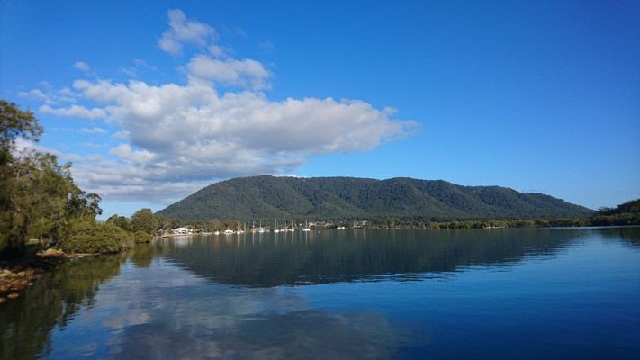 A Lake With Mountains In The Background And Trees On The Shore — Bago Auto Dismantlers in Laurieton, NSW