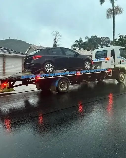 A Tow Truck Is Towing A Car On A Flatbed Trailer — Bago Auto Dismantlers in Laurieton, NSW