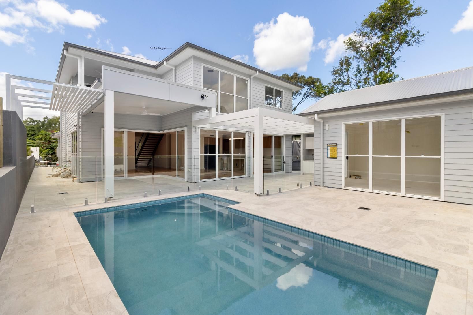 Modern white two-story house with a patio and a backyard swimming pool