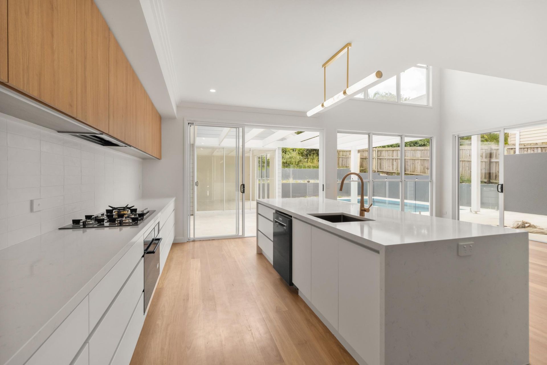 Bright modern kitchen with white cabinets, wood floors, large island, and skylights