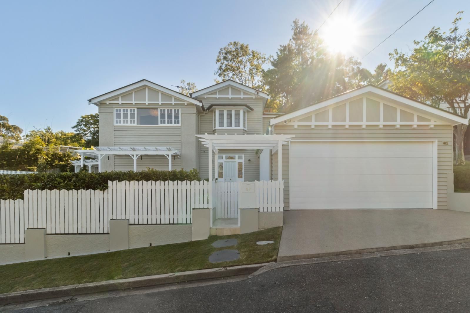 Two-story gray house with white trim, front gate, and large garage at sunset