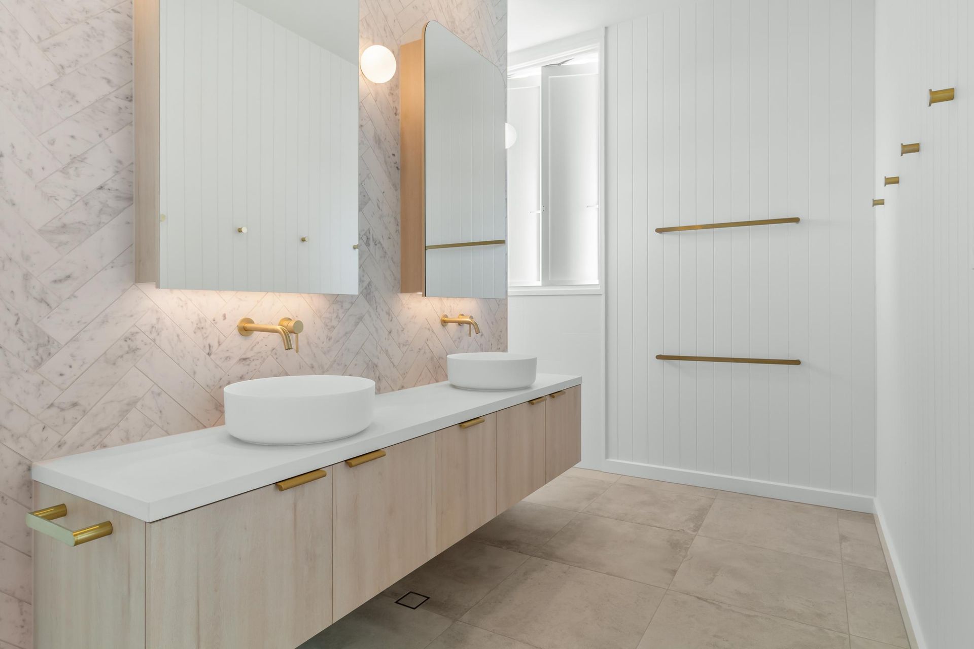 Modern bathroom with double sink vanity, white cabinets, marble walls, and beige tile floor