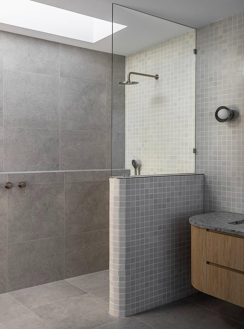 Modern bathroom with walk-in shower, gray tile, and wooden vanity sink.