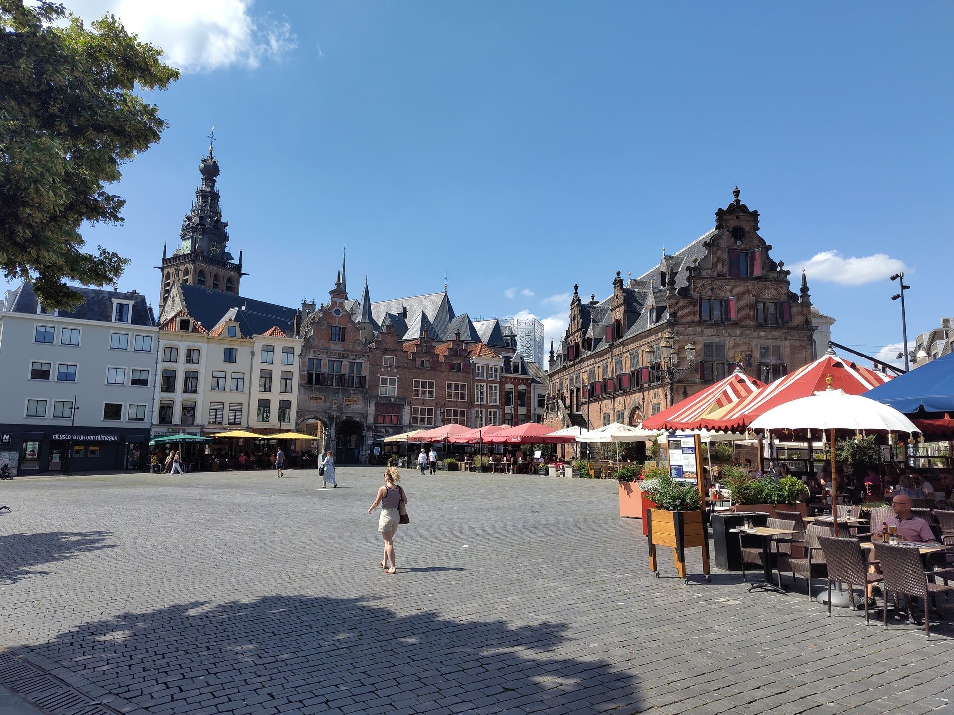Grote Markt Nijmegen, Historisch Europees stadsplein met kinderkopjes, sierlijke gebouwen, terrasjes en een paar voetgangers.