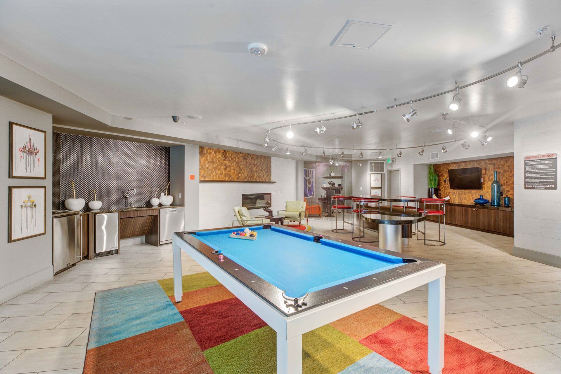 Indoor resident lounge with a blue pool table, seating areas, and a bar/kitchen.