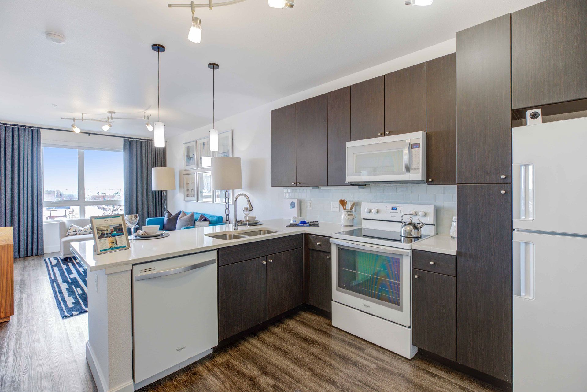 Open-concept kitchen with dark wood cabinets, white countertops, an island, and stainless-steel appliances.