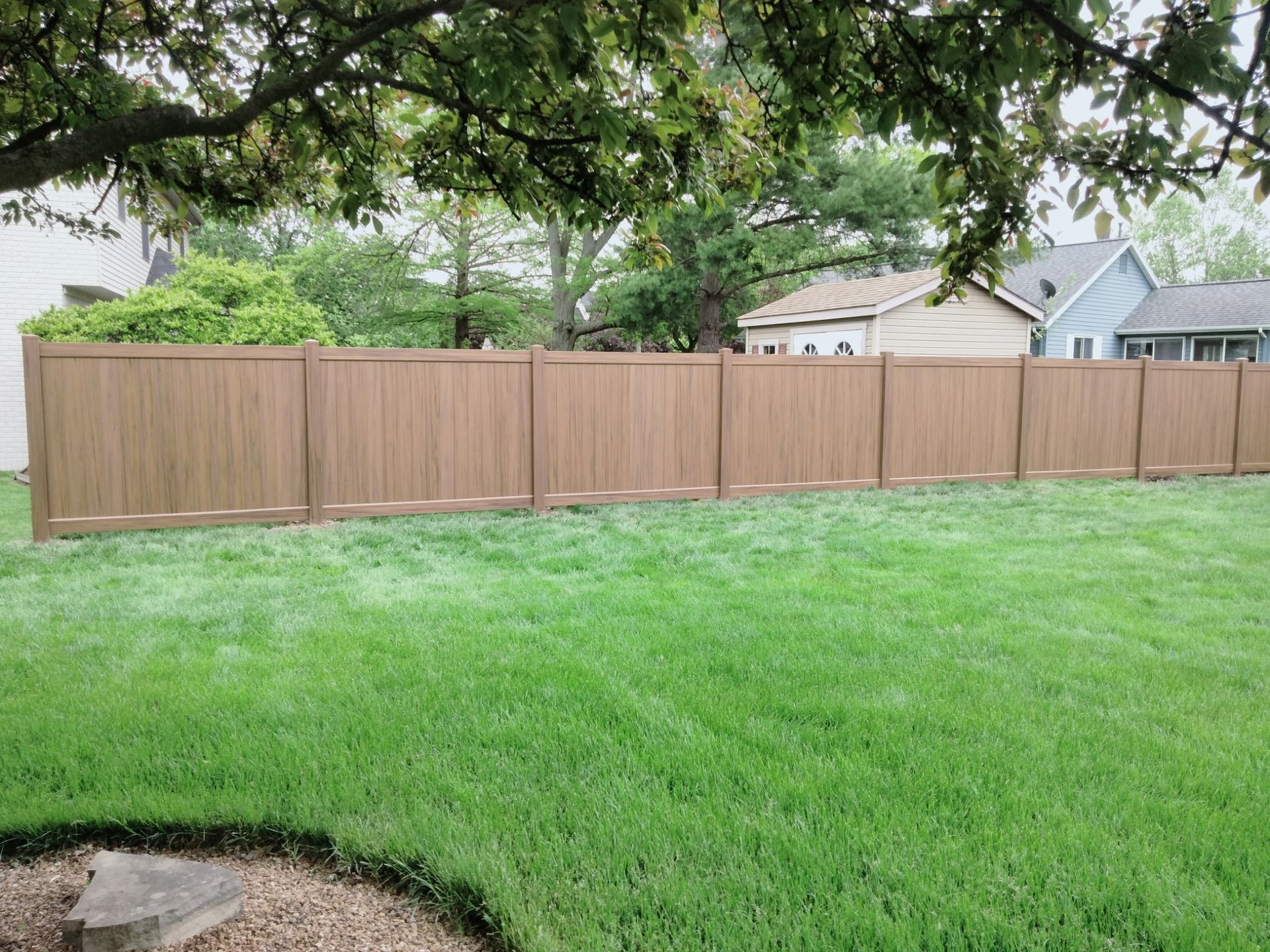 A wooden fence around the house, with a green lawn, installed by a fence contractor. A wooden fence around the house, with a green lawn, installed by a fence contractor.